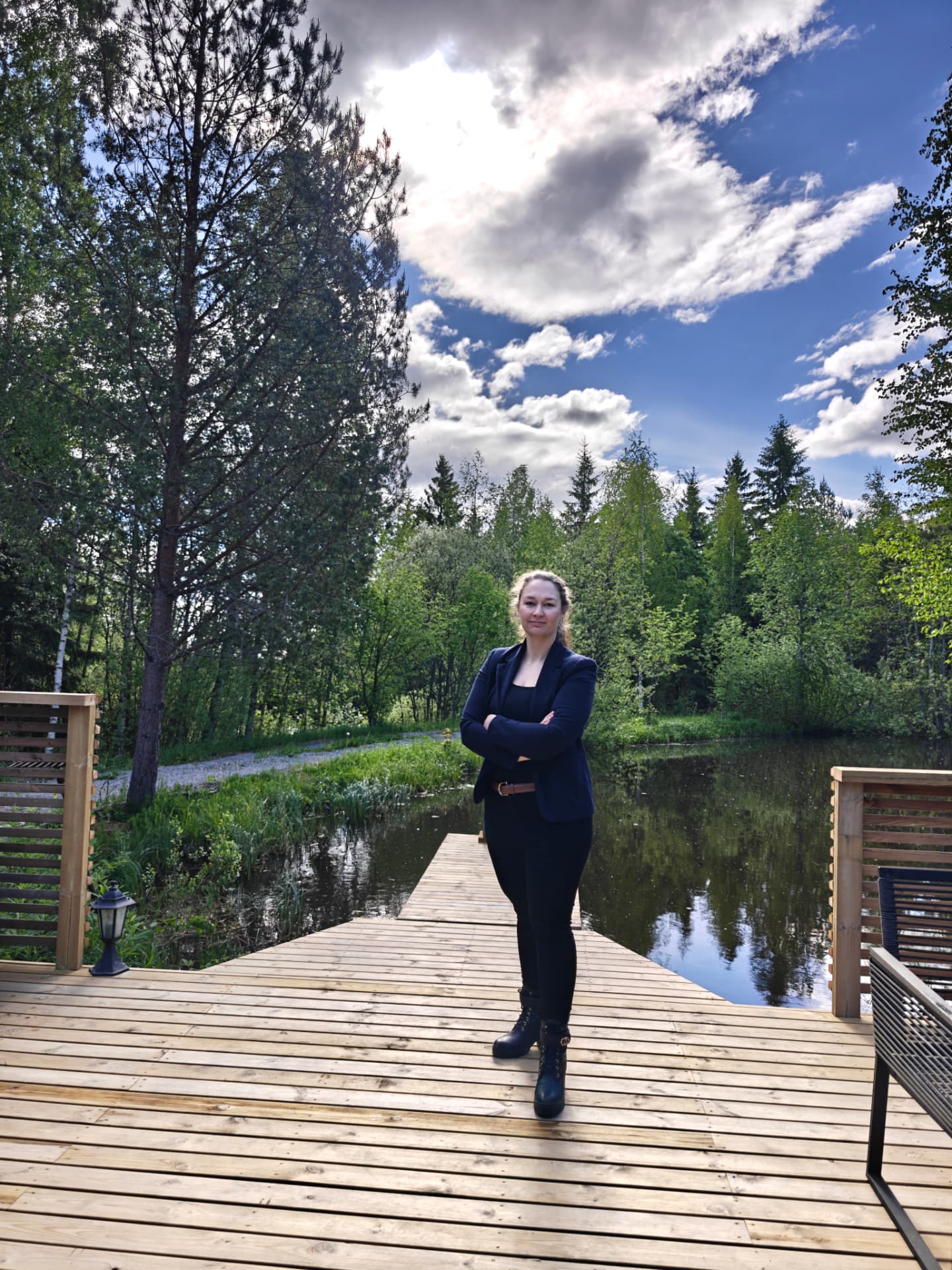 Heidi Uutela seisoo puisella laiturella järven rannalla